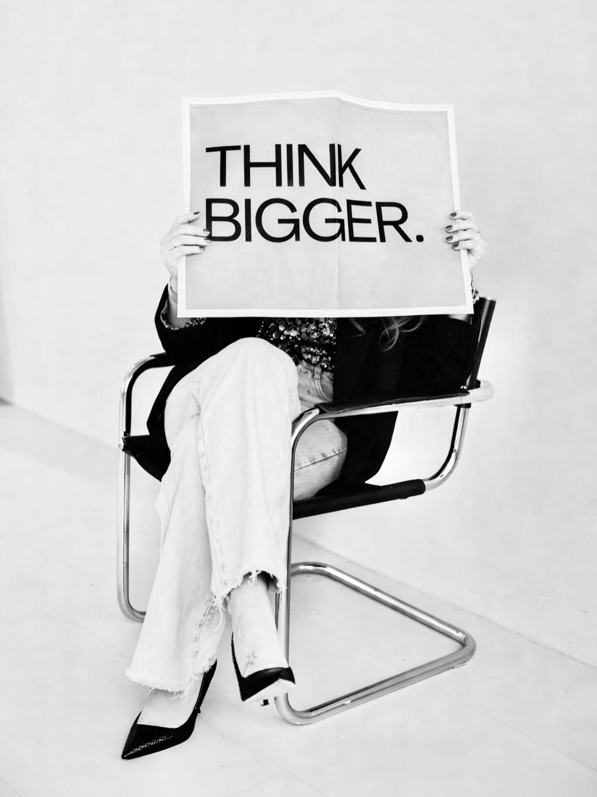 Black and white editorial photograph of a sign reading Think Bigger