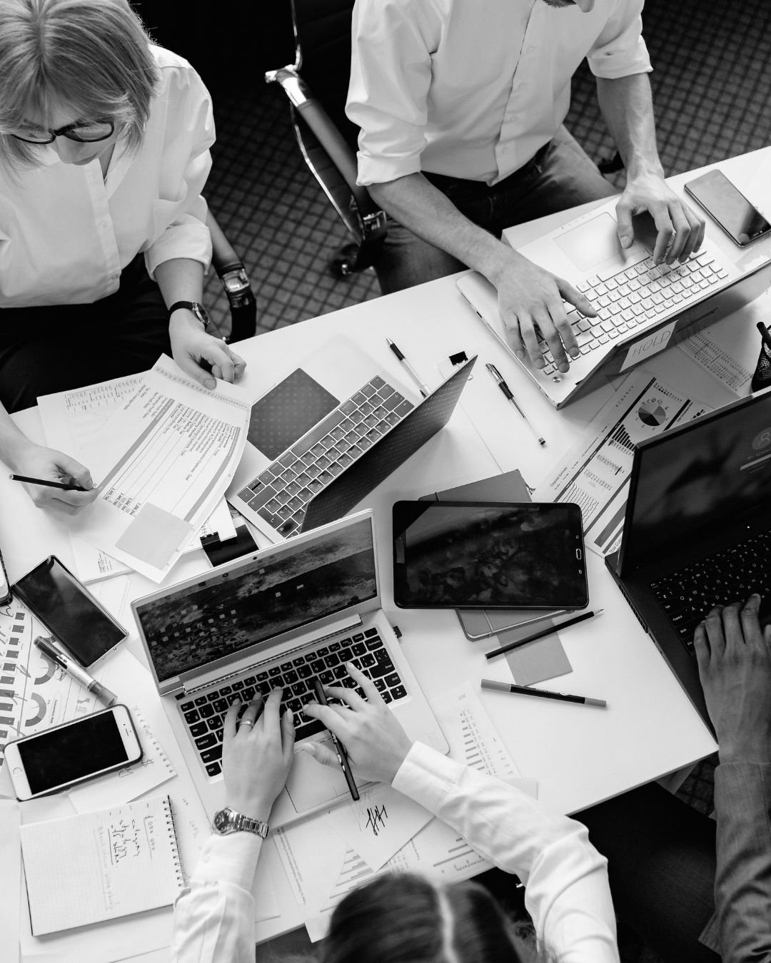 Top-down black and white photo of a team working together at a table